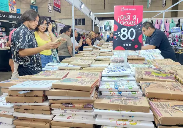 Imagen de jóvenes revisando los libros a la venta en uno de los 250 locales de expositores de la Feria Nacional del Libro de León 2025.