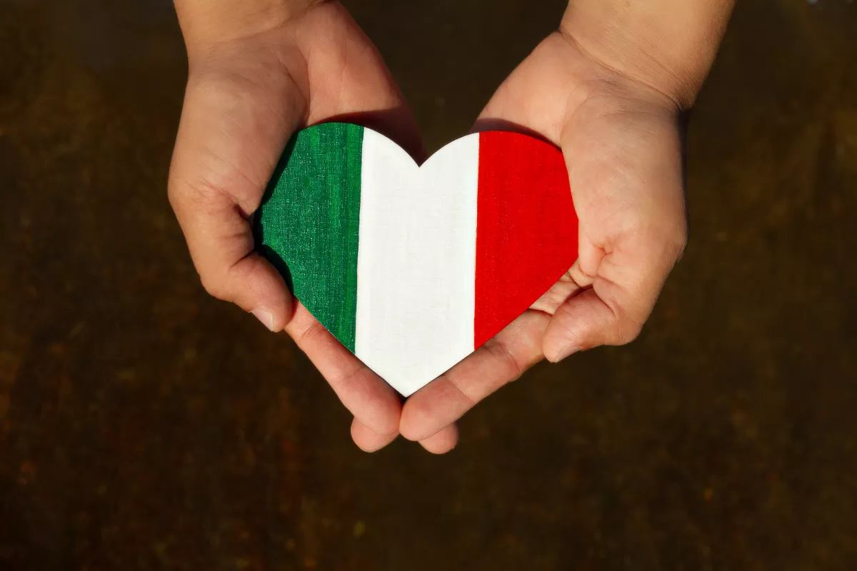 Un hombre sostiene en las manos un corazón de madera, pintado con los colores de la bandera de Italia 