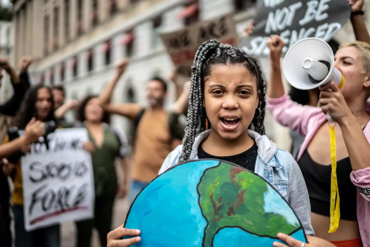 Retrato de una adolescente sosteniendo un cartel en forma de planeta en una protesta ambientalista. 