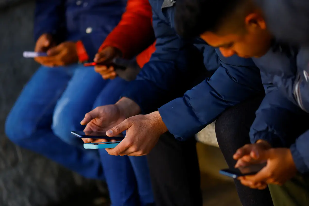 Migrantes que buscan asilo en Estados Unidos utilizando la aplicación CBP ONE de Aduanas y Protección Fronteriza (CBP) de Estados Unidos, esperan afuera del edificio del Instituto Nacional de Migración (INM) mientras hacen cola para solicitar un permiso para viajar a otro punto de entrada a los Estados Unidos para asistir a la cita de inmigración, en Ciudad Juárez, México 22 de febrero de 2023.