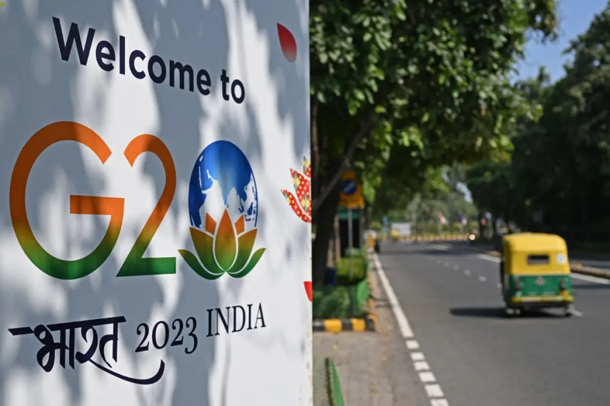 Un auto-rickshaw pasa por delante de una valla publicitaria instalada a lo largo de una calle antes de la cumbre de dos días del G20 en Nueva Delhi el 5 de septiembre de 2023.