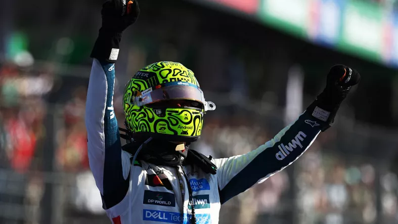 Foto de Lando Norris con casco de McLaren y los brazos levantados en señal de victoria al salir de su monoplaza en el GP de México 2025.