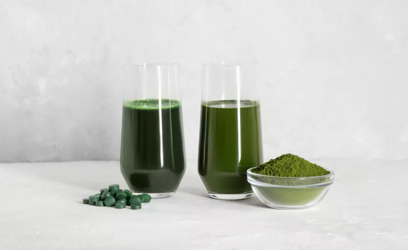 Chlorella and spirulina green drinks on a white concrete background. Spirulina tablets and chlorella powder. Superfood concept. Detox drinks. Copy space.
