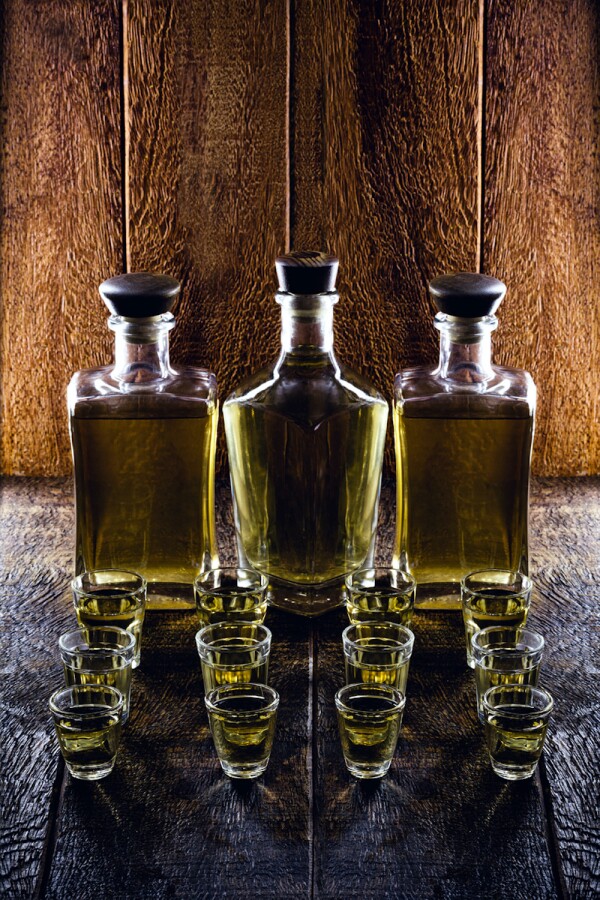 The luxurious and unexpected gifts this year will receive the Oscar Nominees 19 glass of alcoholic beverage, with bottle in the background, rustic setting. Brazilian gold type cachaça, called pinga.