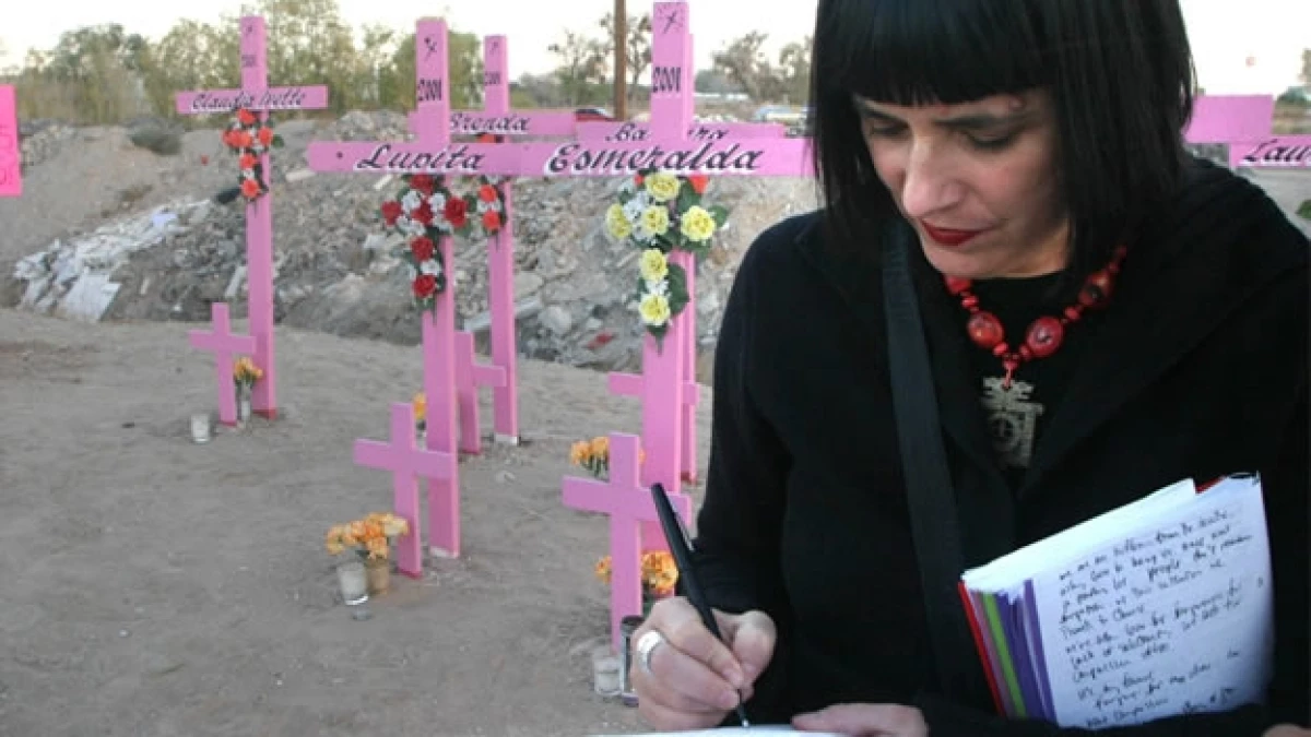 Una escritora y activista escribe frente a las cruces rosas con los nombres de decenas de mujeres asesinadas en Ciudad Juárez, Chihuahua