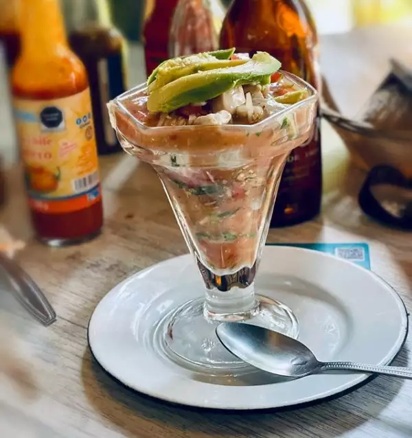 Foto de un tradicional ceviche de pescado en copa con aguacate encima.