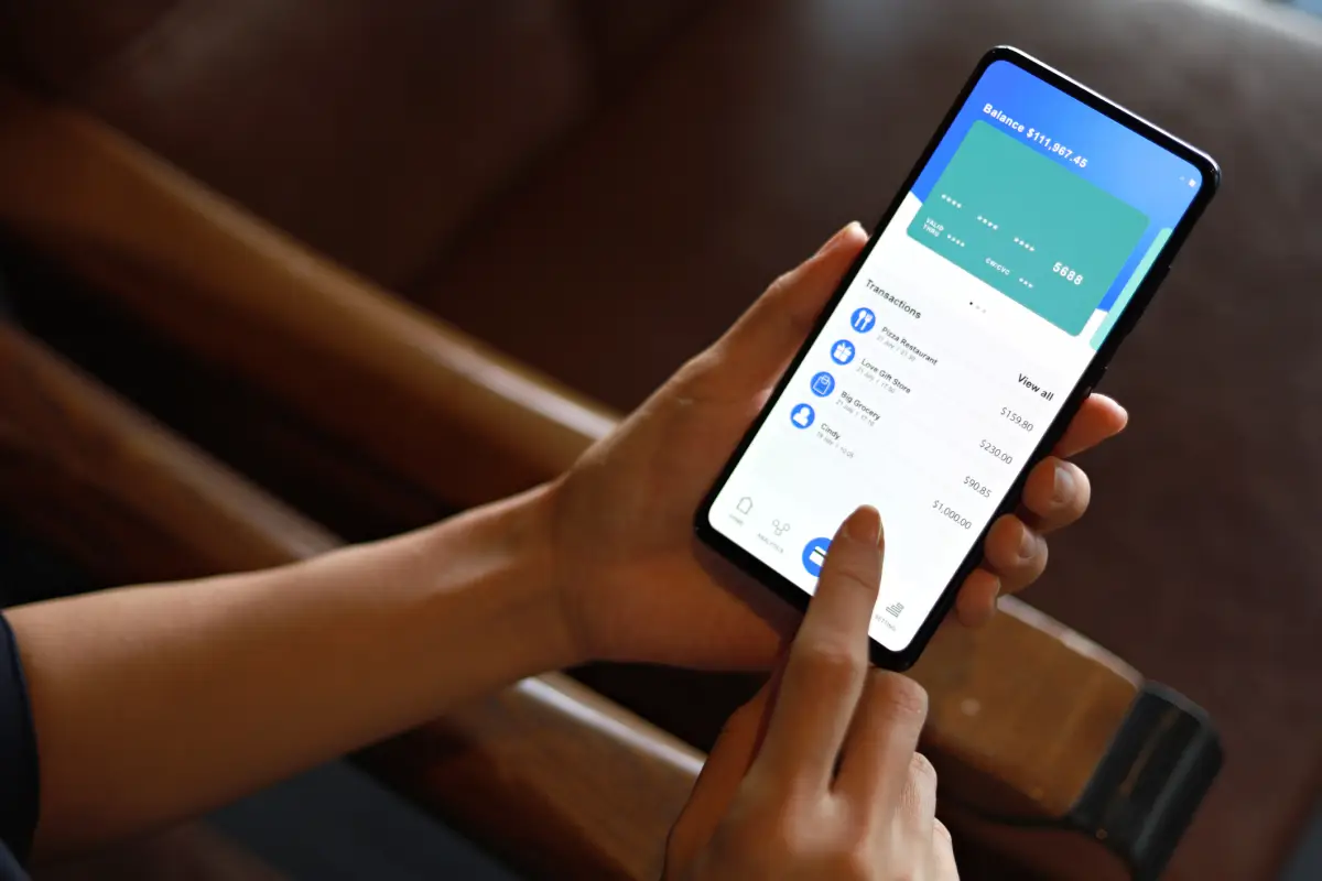 La imagen muestra una mujer consultando su cuenta bancaria y sus gastos mediante su dispositivo móvil. Comodidad y facilidad en la gestión bancaria gracias a la tecnología.