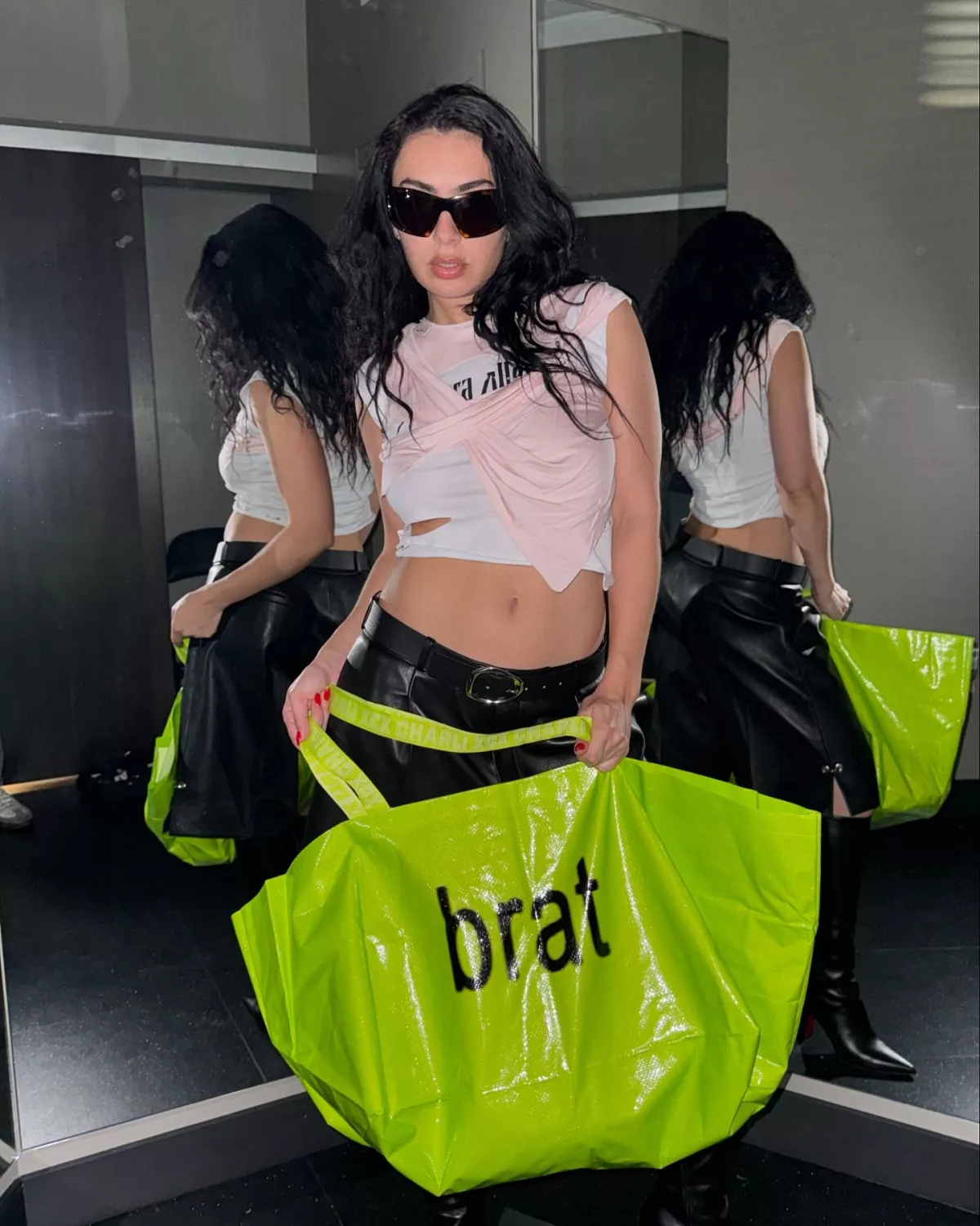 Foto de Charli XCX cargando una bolsa verde brillante con la palabra BRAT escrita.