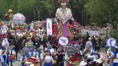 Dos catrinas gigantes con huipiles. Hombres y mujeres vestidos de blanco y azul con maquillaje de catrinas.jpg