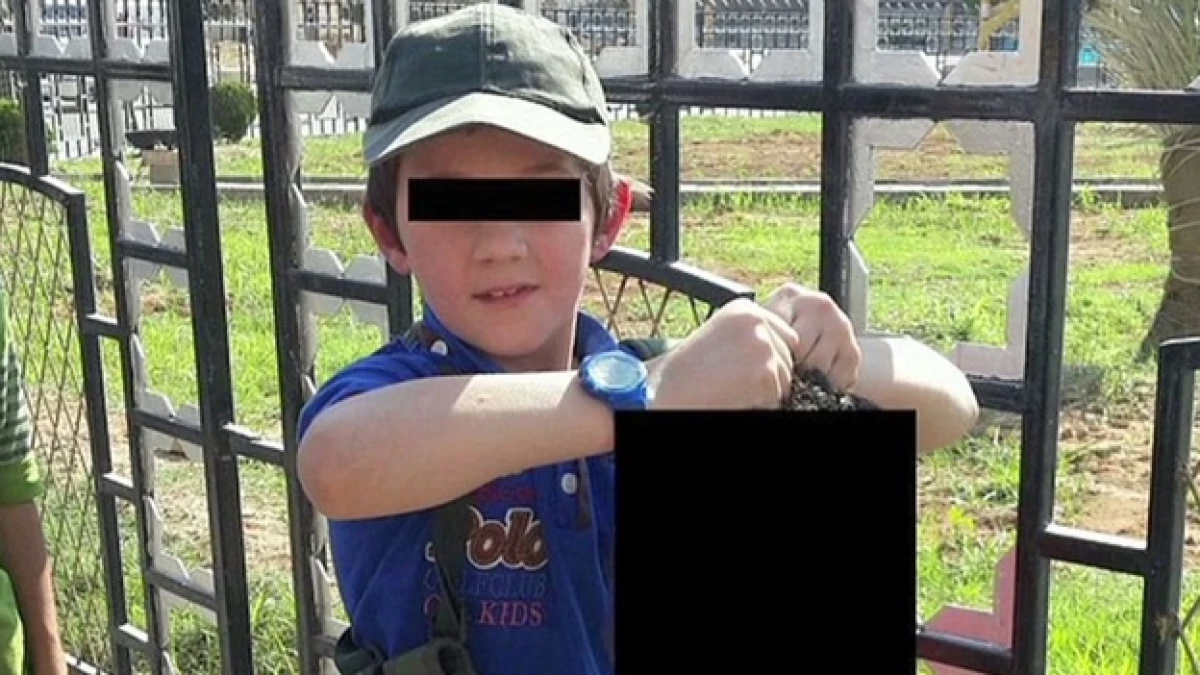 niño sosteniendo a un decapitado de isis