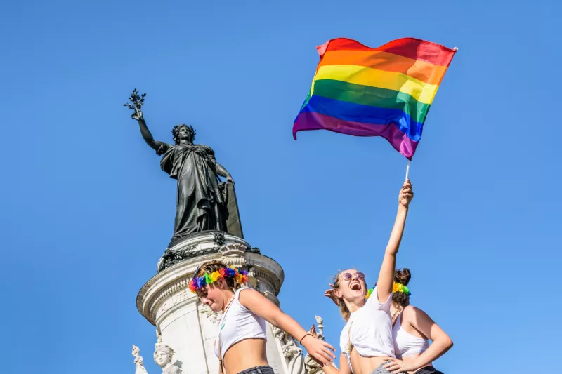 A young woman waves a rainbow flag high during the Gay Pride parade in Paris, France.