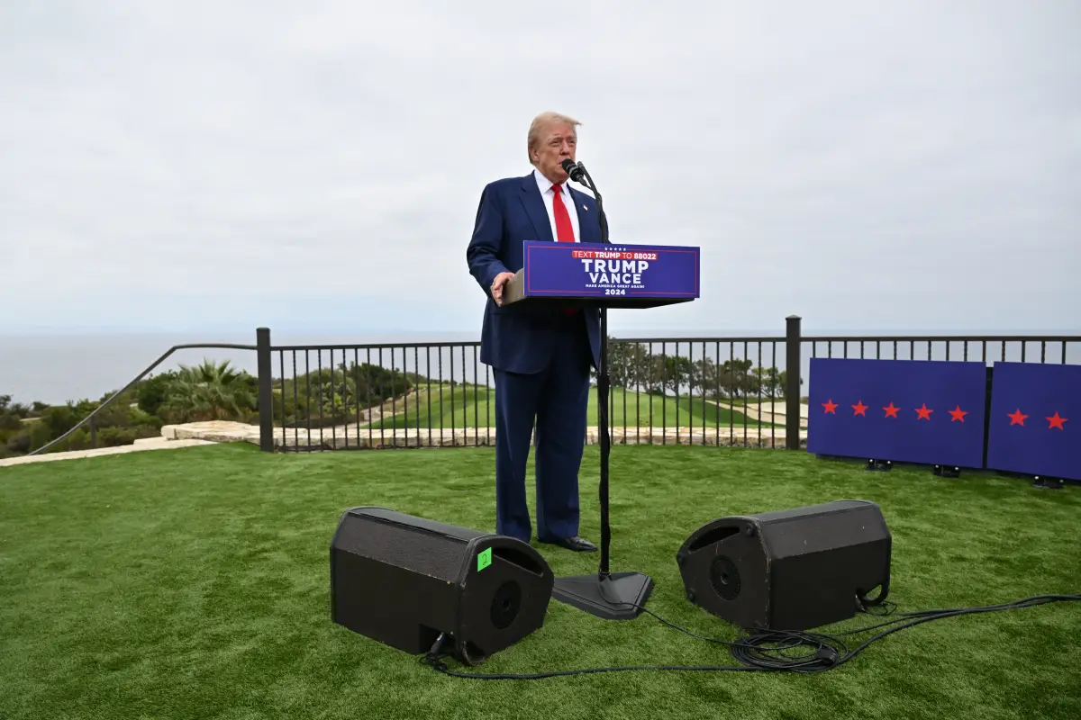Trump, un hombre blanco de 78 años, regresa a la campaña luego de su segundo intento de asesinato. En la imagen se aprecia a Trump dentro del 'Trump National Golf Club' con un traje azul marino y corbata roja dando una conferencia de prensa.