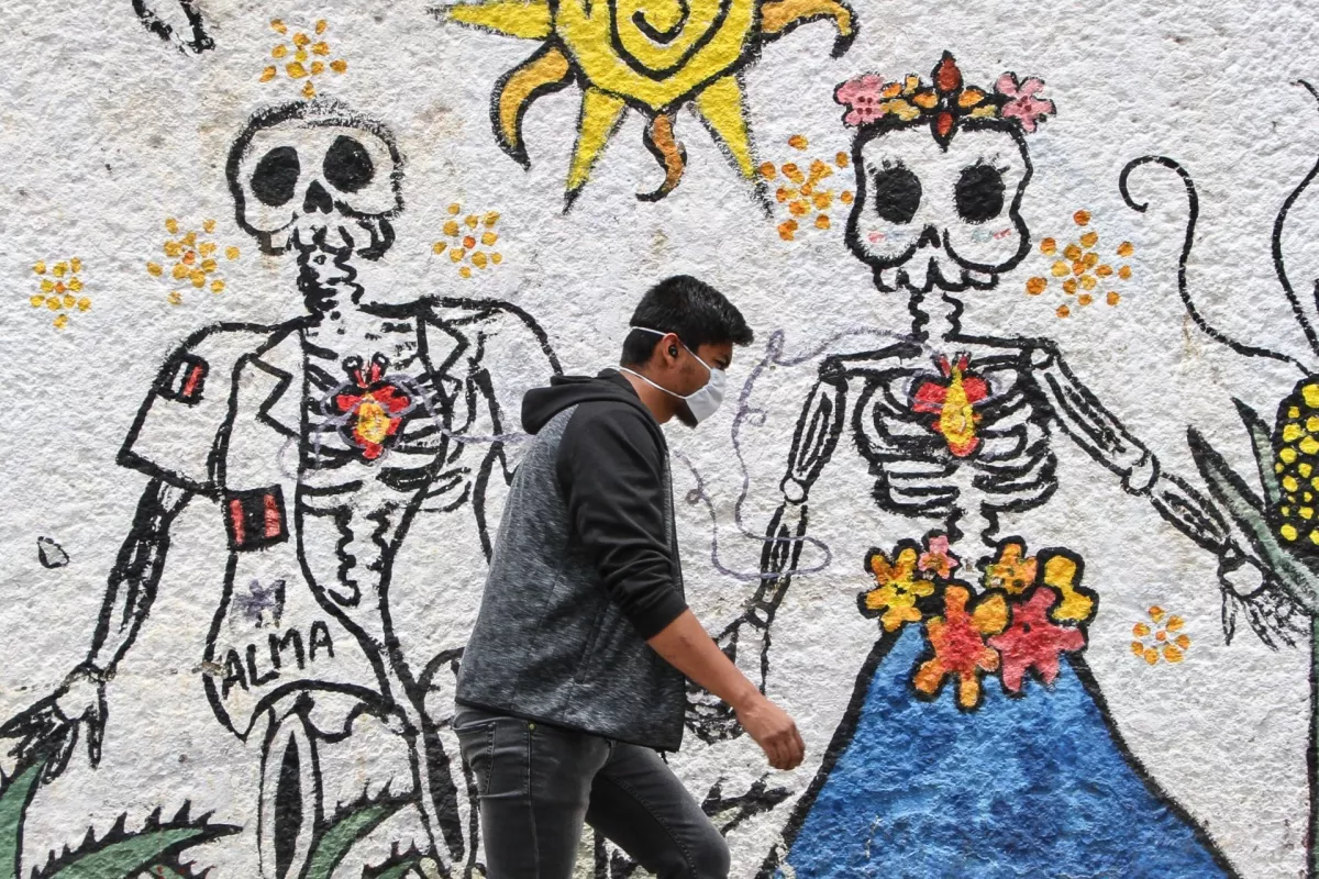 Ciudadanos caminan entre murales alusivos a la muerte en una de las colonias más infectadas por COVID-19.
