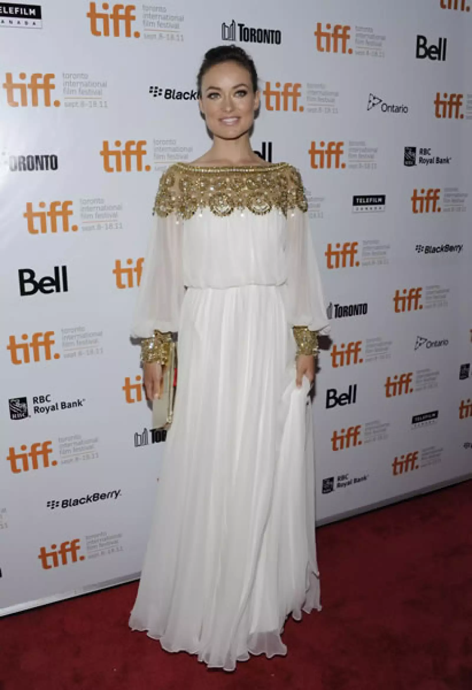 Olivia Wilde luce espectacular en este vestido Marquesa con detalles dorados en todo el cuello del vestido y las muñecas.