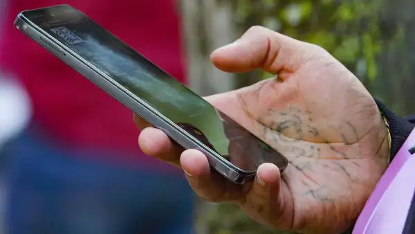 Una mano con un tatuaje en la palma sostiene un celular. 