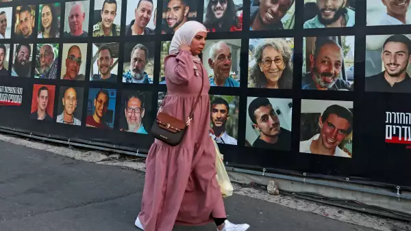 Una mujer pasa por una valla publicitaria con los retratos de israelíes retenidos como rehenes en la Franja de Gaza por militantes palestinos desde 2023, en Jerusalén el 6 de octubre de 2025.