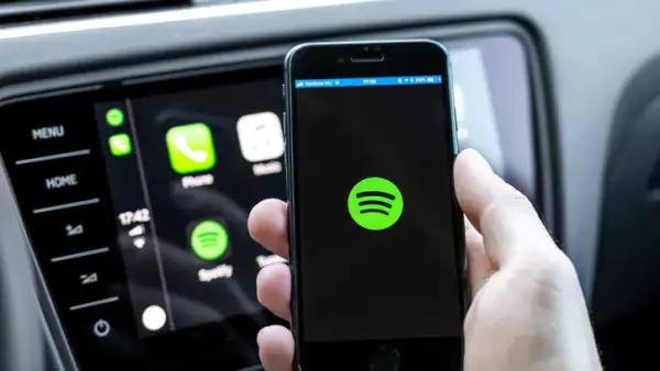 Male hands holding a smartphone that is connecting to the car's computer running the popular music streaming service