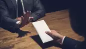 Businessman rejecting money in white envelope offered by his partner in the dark