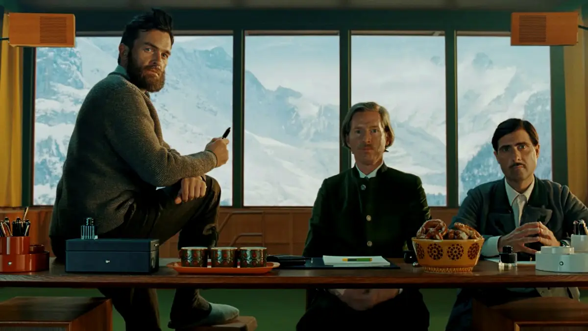tres hombres ante un escritorio con plumas estilográficas y papeles, al fondo se observa el Mont Blanc.