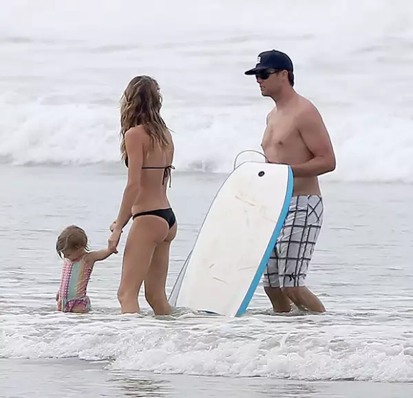 Tom enseña a sus hijos a divertirse en la playa.
