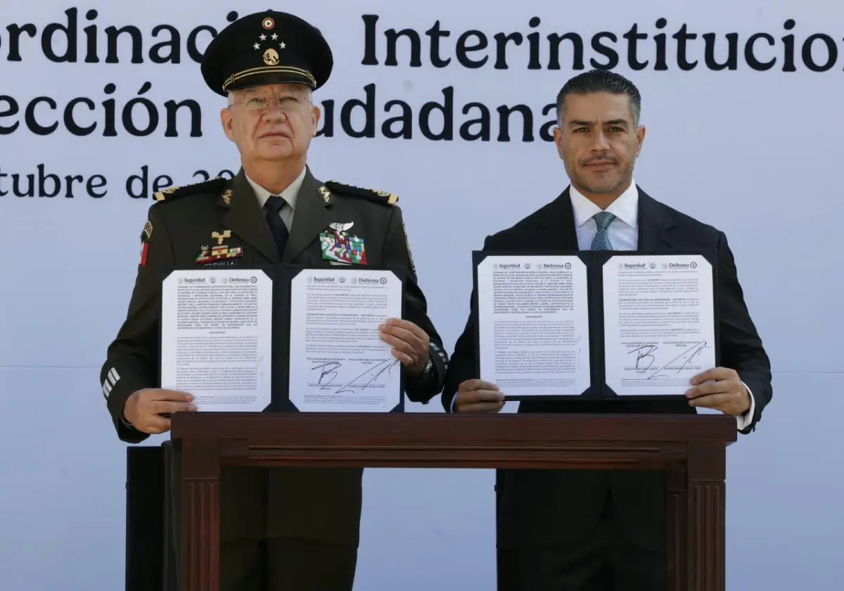 En la imagen, los  secretarios Omar García Harfuch y Ricardo Trevilla sostienen el convenio tras la firma. 