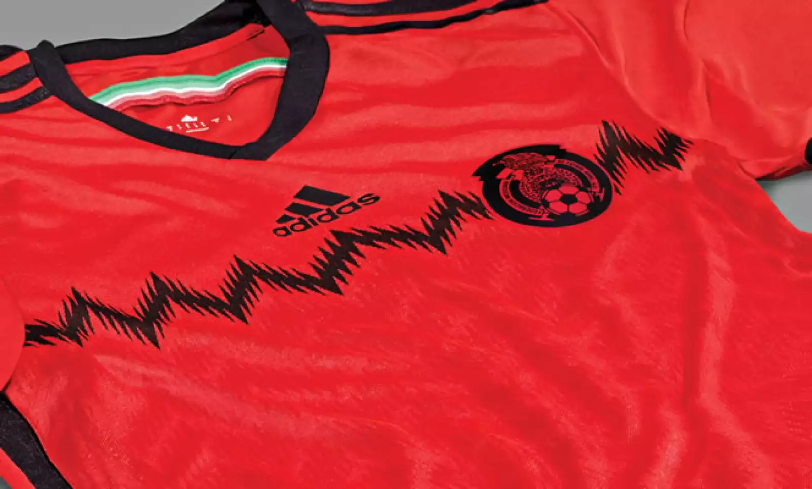 El escudo de la FMF se encuentra ubicado a la altura del corazón en una aplicación dicromática. Debajo de él se encuentra un gráfico de grecas negras que se repite en tonos rojos de manera sutil en la parte frontal.