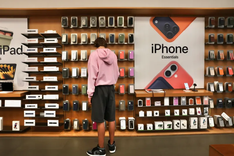 Persona parada frente a una estantería de Apple eligiendo accesorios para iPhone en una tienda de la marca en Manhattan, Nueva York.