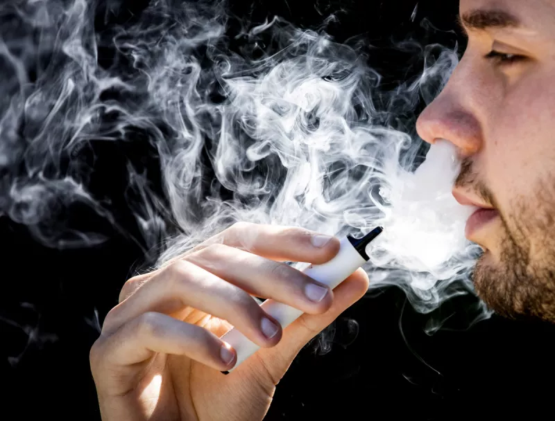 Persona fumando en un vapeador. 