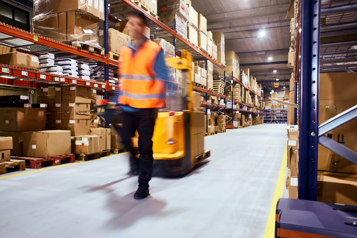 Warehouse, worker with a forklift in motion blur.