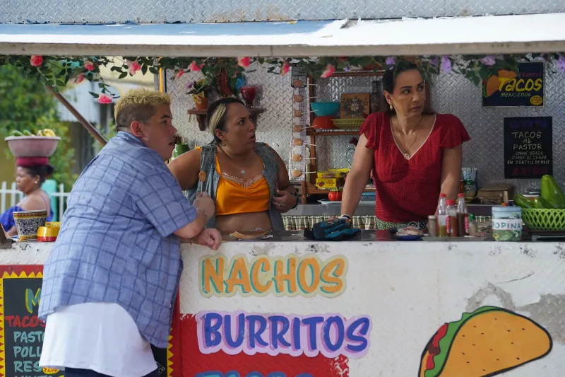 Imagen de la película Canta y no llores, en donde se observa una mujer que es la dueña del puesto, así como sus hijos, en un puesto de comida en la calle.