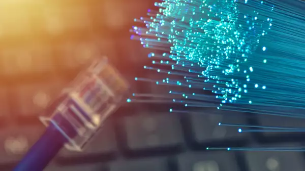 Fiber optics in blue, close up with ethernet and keyboard background, warm lens flare