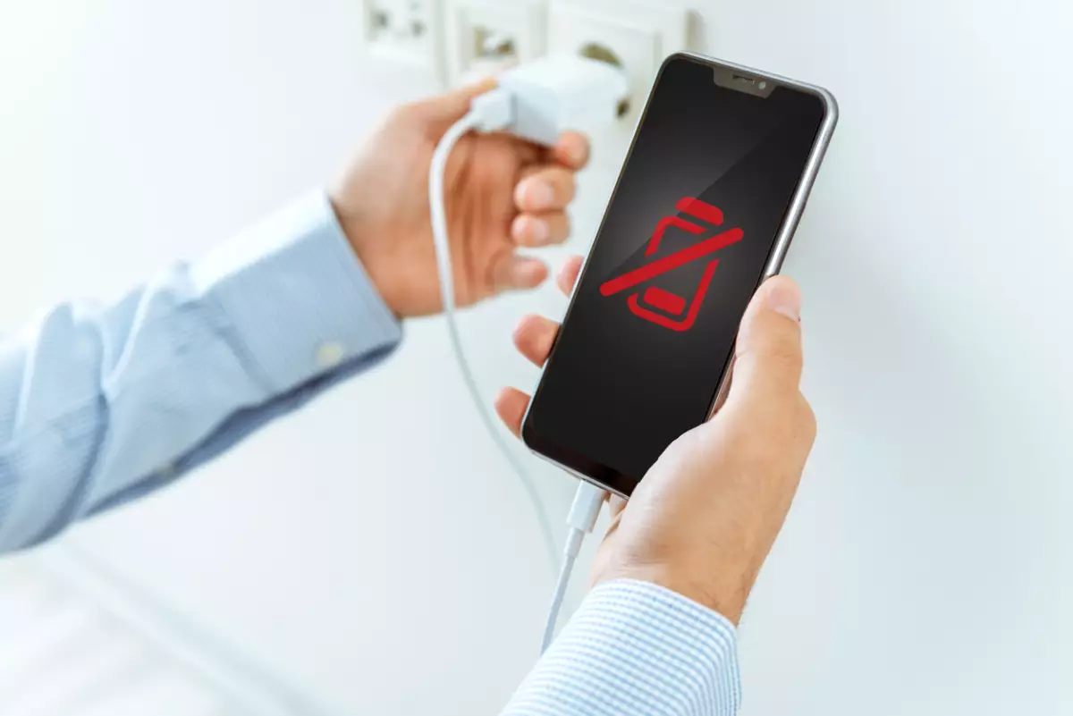 Caregador de celular conectado a un smartphone con batería agotada.