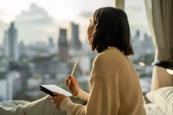 Asain woman writing her to-do list on digital tablet