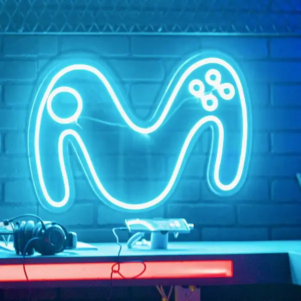 El logo de la empresa Movistar iluminada y pegada a una pared en un cuarto de jugadores de videojuegos 