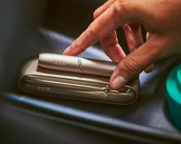 Una mujer sostiene un IQOS en el interior de su coche