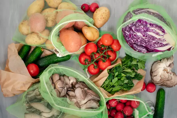 Vegetable in reusable bags on wood background, top view