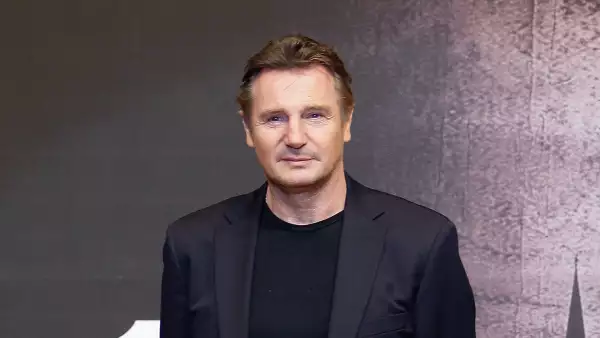 El actor Liam Neeson con playera y saco color negro y gesto serio.