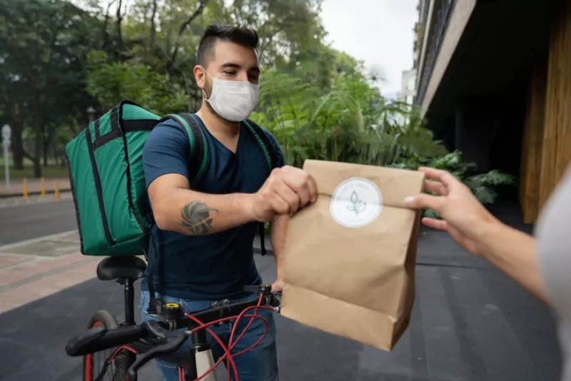 Un repartidor de comida vía plataforma, hace entrega de un pedido.