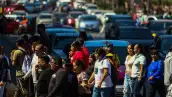 Personas cruzan una avenida frente a autos que esperan en la Ciudad de México.