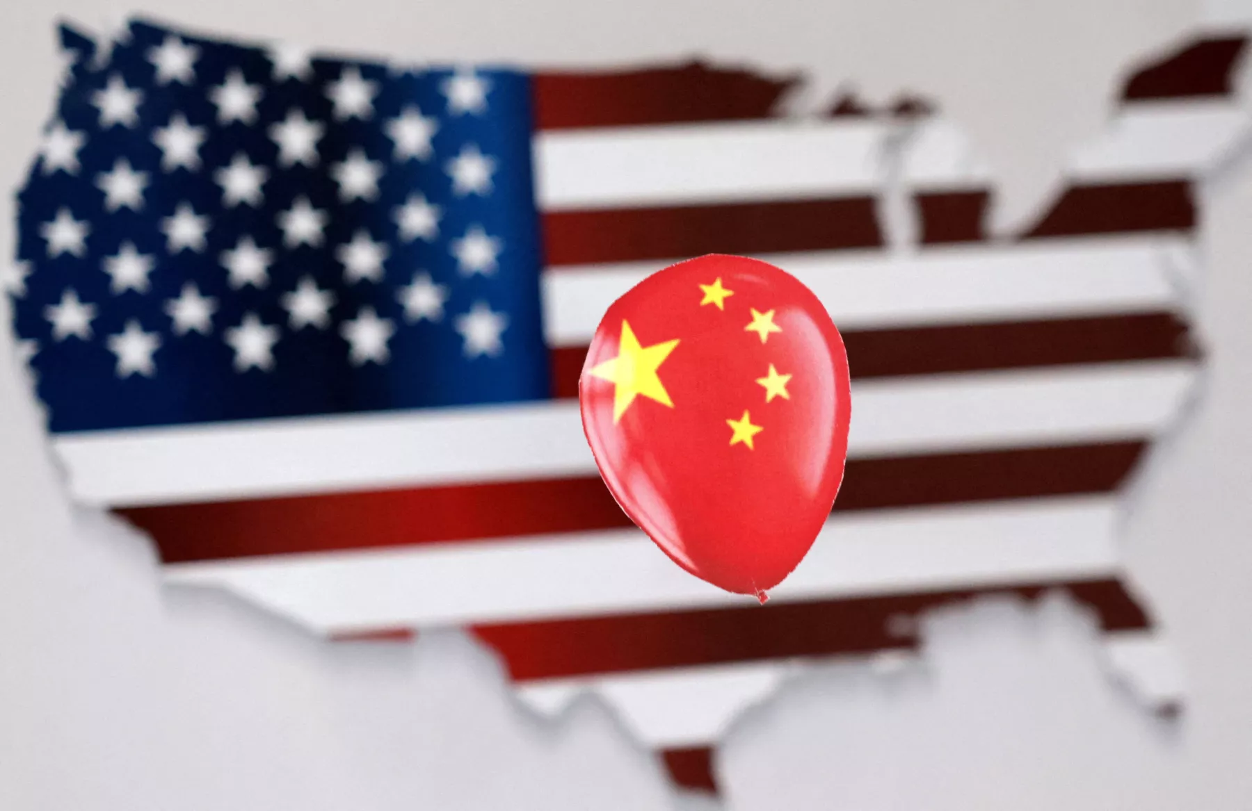 Una ilustración muestra un globo impreso con una bandera de China puesto arriba de una bandera de Estados Unidos en forma de Estados Unidos. 