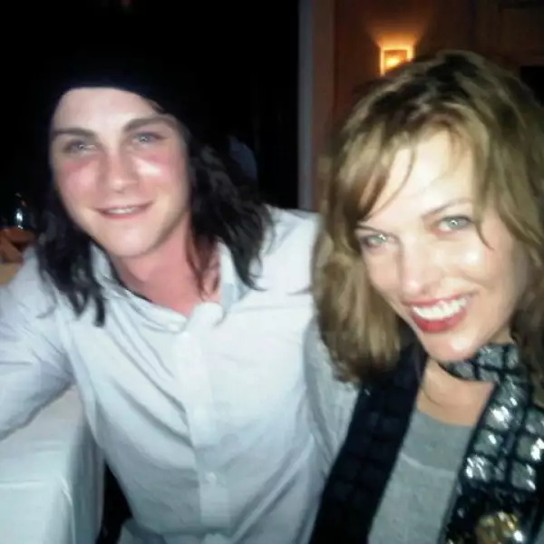 La actriz Milla Jovovich sonriente y acompañada.