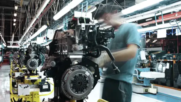 Un trabajador participa en la colocación de tornillos para la fabricación de un motor en una planta de autopartes en México. 