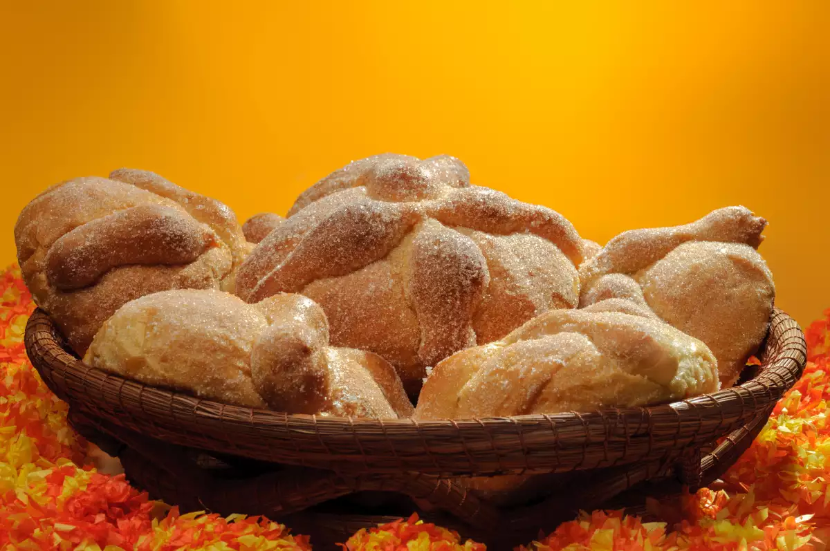 Pan de muerto en una canasta con un fondo naranja.