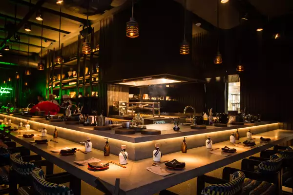 Restaurante de comida china con poca luz y barra de sushi.