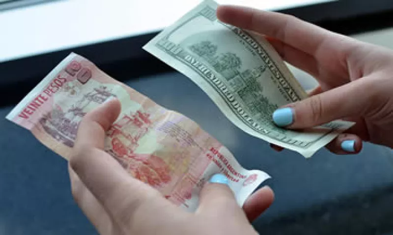 Unos 20 pesos argentinos y 100 dólares son sostenidos por una persona en un casa de cambio de Argentina (Foto: Getty Images)