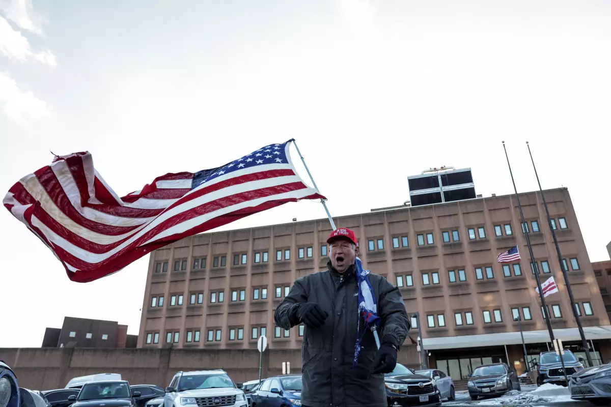 Un hombre lleva una bandera estadounidense fuera de un centro de detención, en el que algunas personas que participaron en el ataque del 6 de enero de 2021 contra los Estados Unidos El Capitolio se celebra, el día de la inauguración del segundo mandato presidencial de Donald Trump en Washington, EE. UU. 20 de enero de 2025. Los partidarios esperan que EE. UU. El presidente Donald Trump emitirá indultos para algunos de los cargos relacionados condenados el 6 de enero.