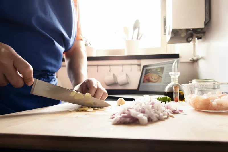 hands of a man in the kitchen chopping vegetables
