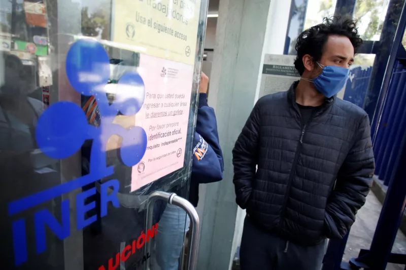 People wearing protective face masks wait in line outside the National Institute of Respiratory Diseases where a patient who tested positive for coronavirus is being treated, according to local authorities, in Mexico City
