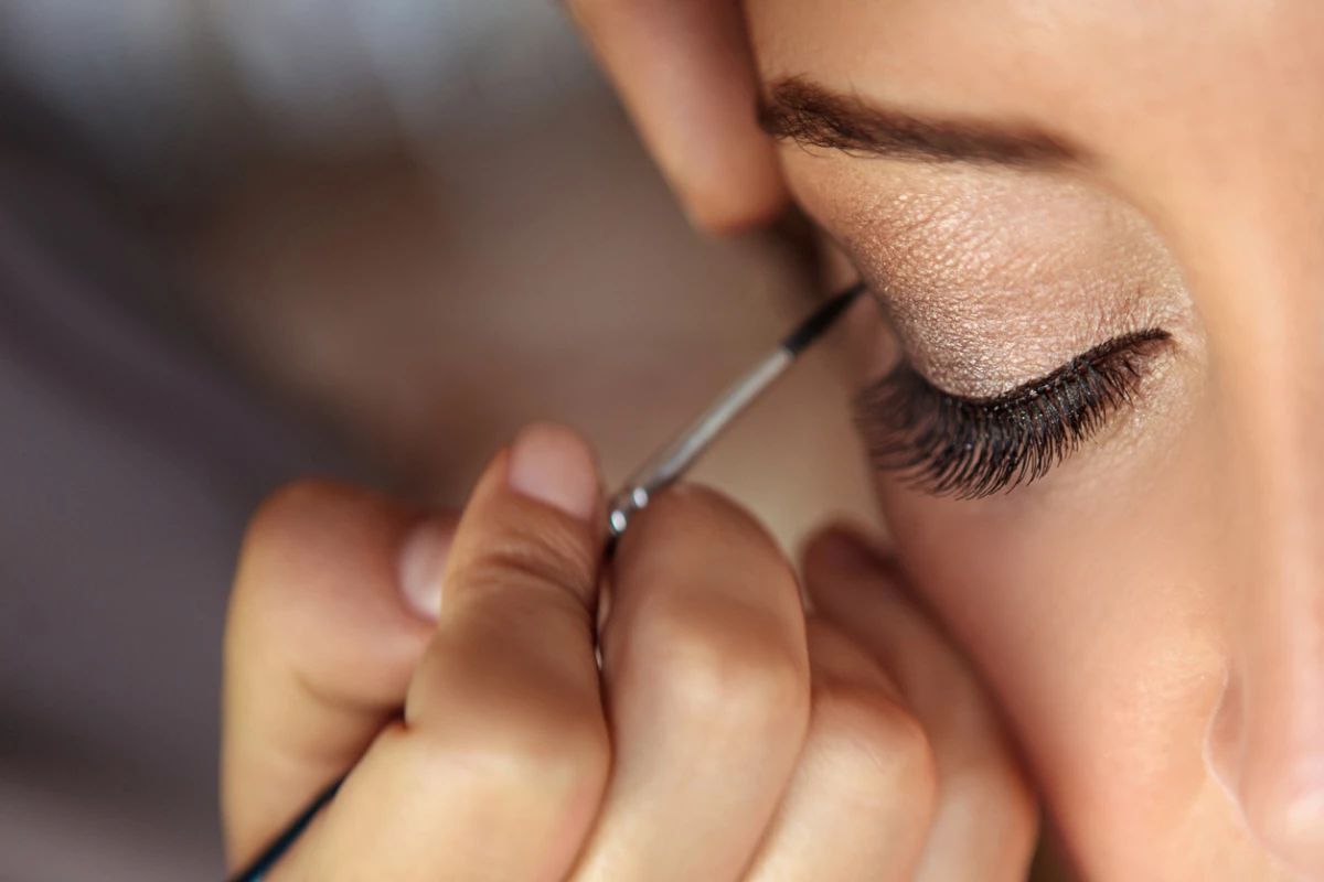 Beautiful fashion model applying makeup by makeup artist.