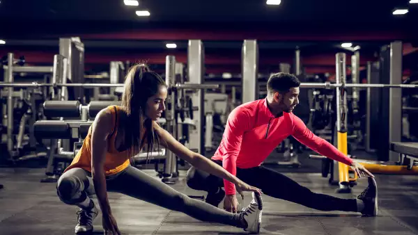 (Mujer entrenado junto con su entrenador en un gimnasio)